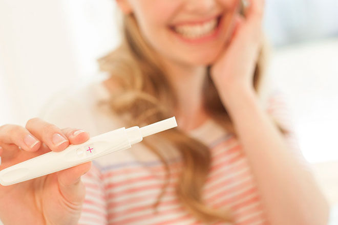 Счастливая девушка с тестом на беременность
