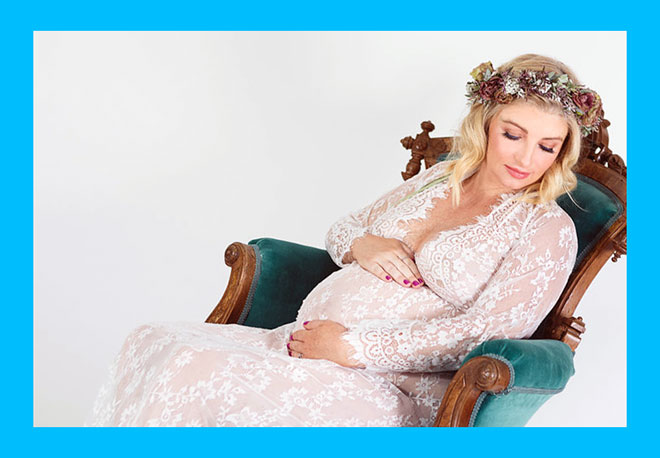 беременная женщина с венком на голове и в красивом платье сидит на кресле
