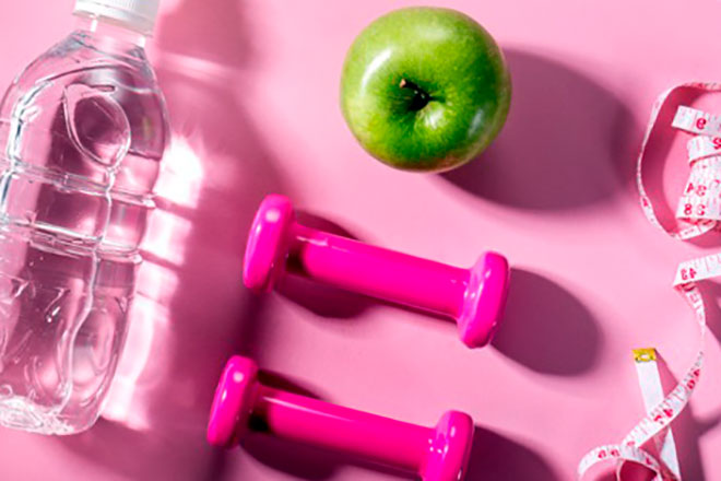 бутылка с водой, зеленое яблоко и метр на розовом фоне