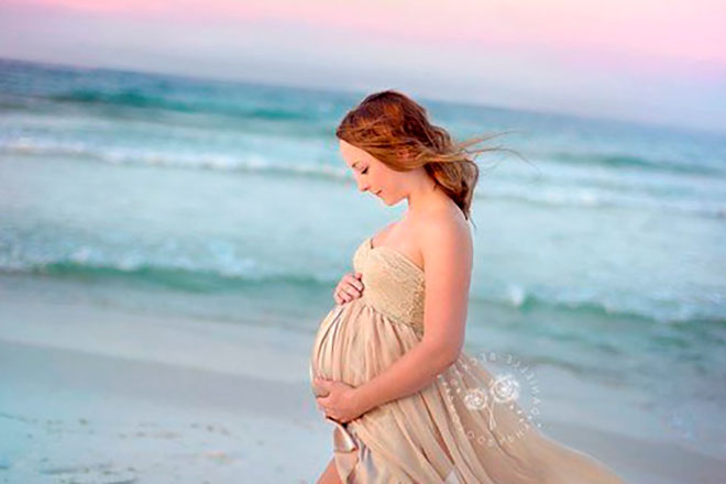 беременная девушка на берегу моря в красивом длинном платье
