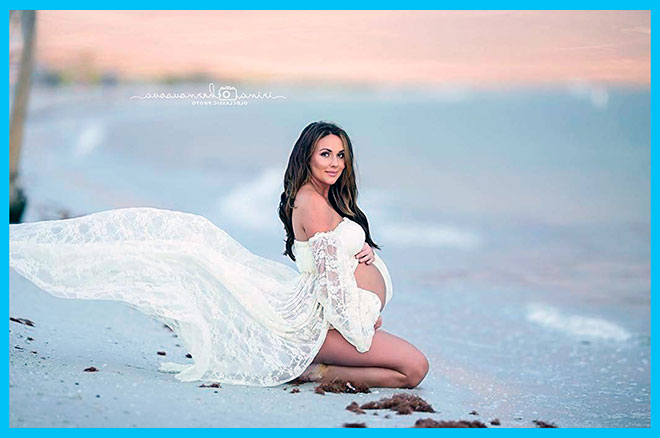 беременная девушка сидит на коленях у моря