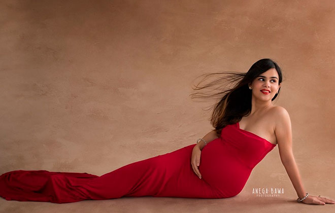 красивая беременная девушка позирует в красивом красном и длинном платье