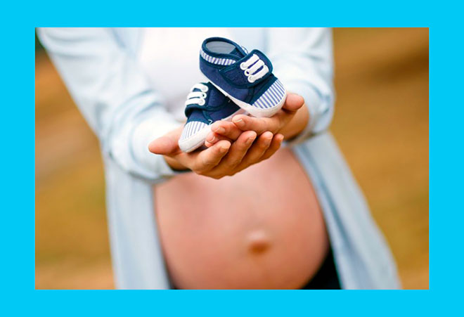 беременная женщина держит на руках детские ботиночки
