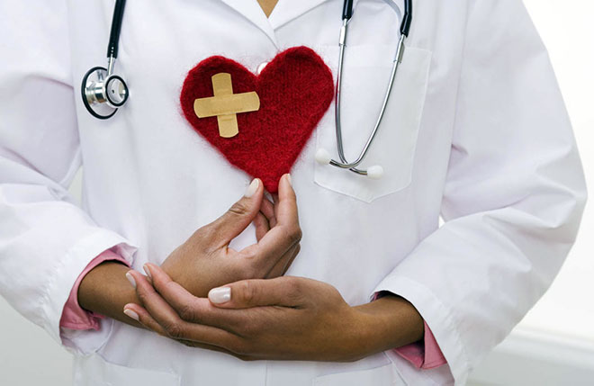 женщина врач держит плюшевое сердце